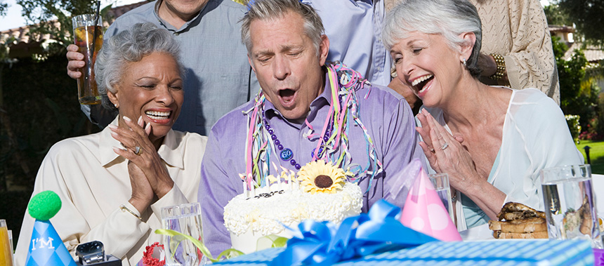 A group of older people celebrating a birthday outside in a backyard