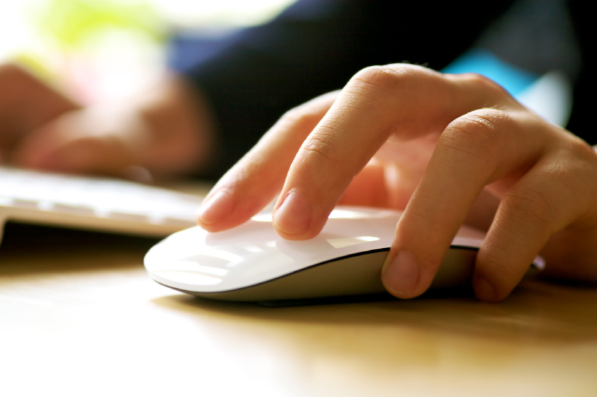 Close-up of a hand on a white mouse next to a keyboard