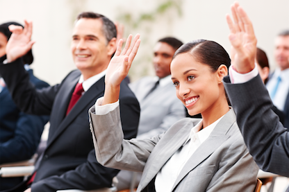 Businessmen and businesswomen participating in a seminar raising their hands