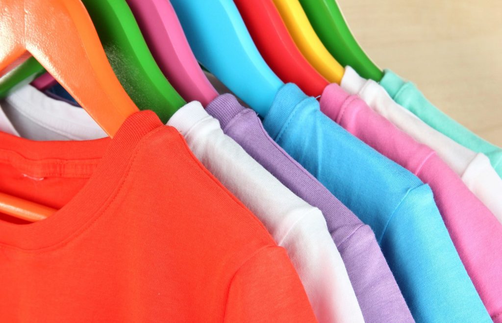 An array of colorful t-shirts hanging on colorful hangers