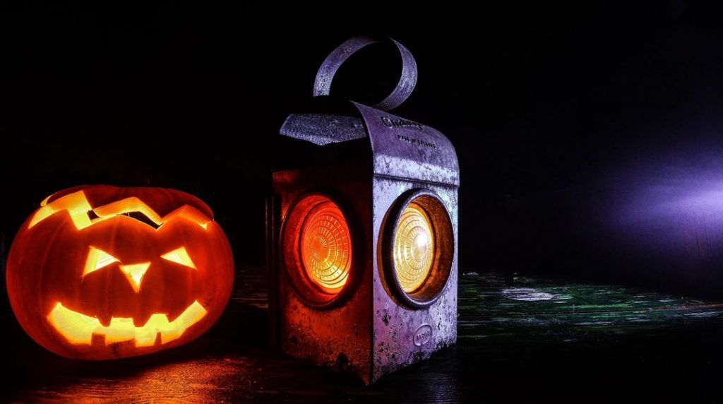 A jack-o'-lantern and a lantern alight at night