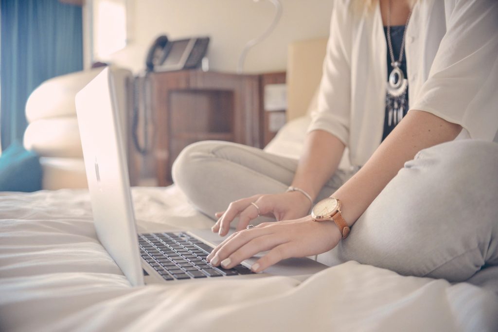 A woman sitting cross-legged on a bed working on a laptop
