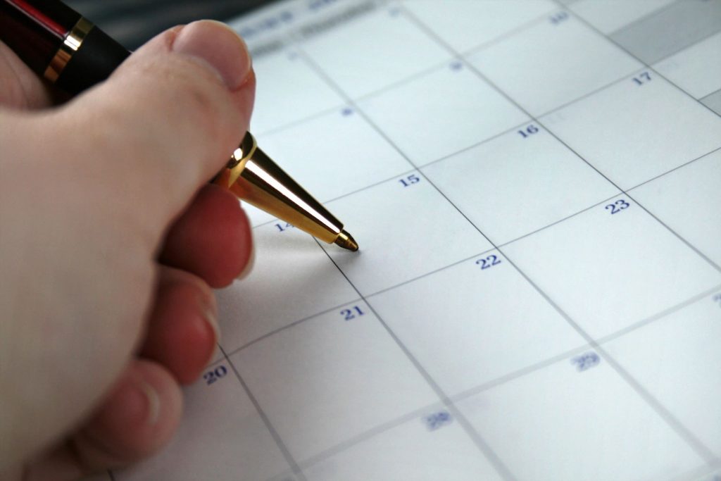 Close-up of a hand holding a pen on top of a calendar
