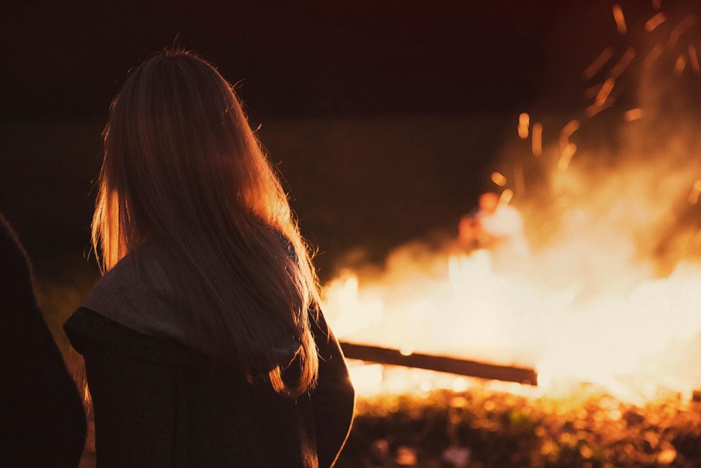 A view of a girl from behind in front of a bonfire