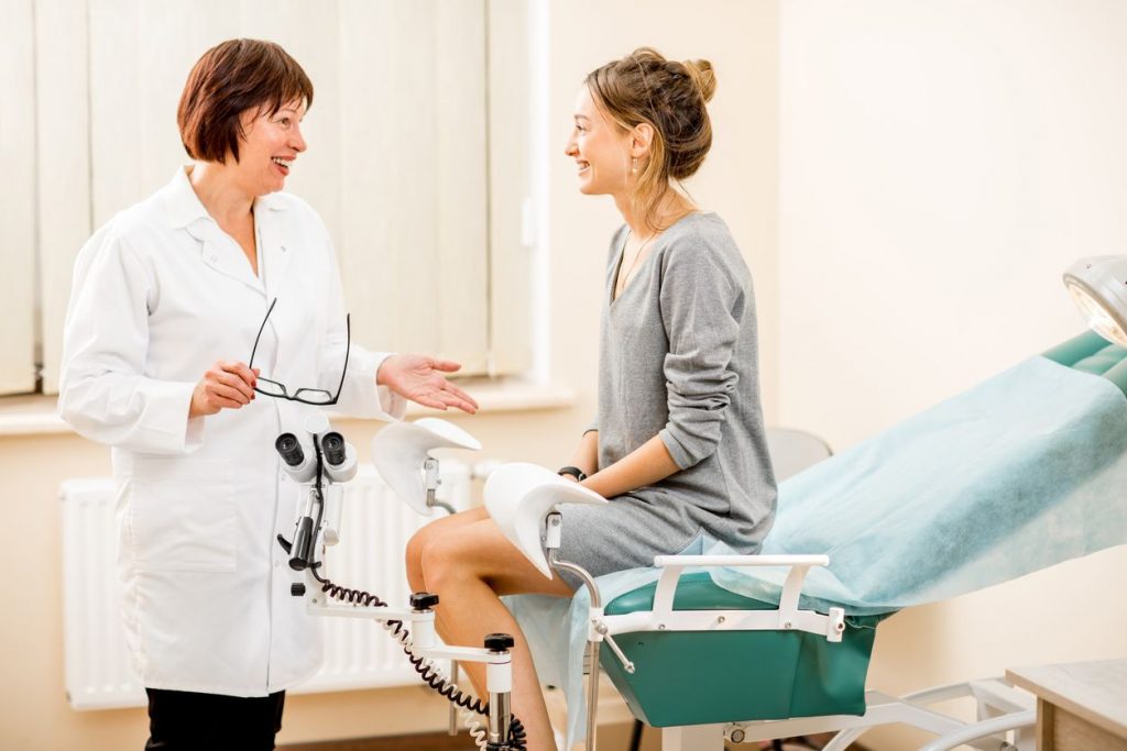 A female doctor smiling and conversing with a female patient in a medical examination room
