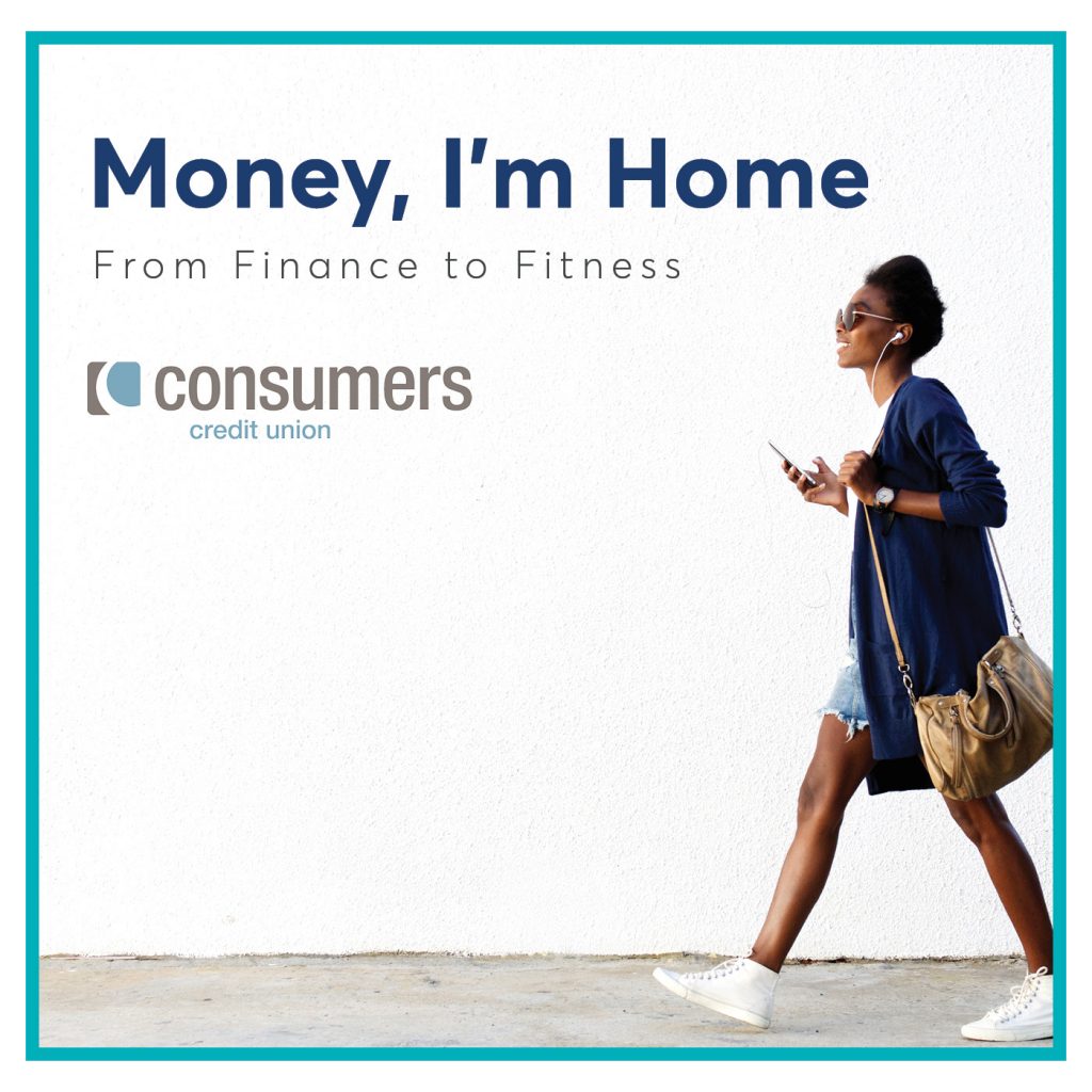 A woman walking and listening to a pair of earbuds in front of a white wall with the Consumers Credit Union logo