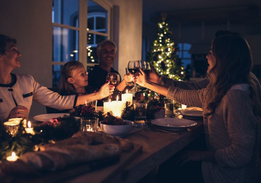 A happy family clinking glasses during a Christmas season dinner at a candle-lit table