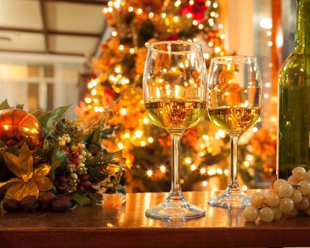 Two glasses of white wine in front of a lit-up Christmas tree