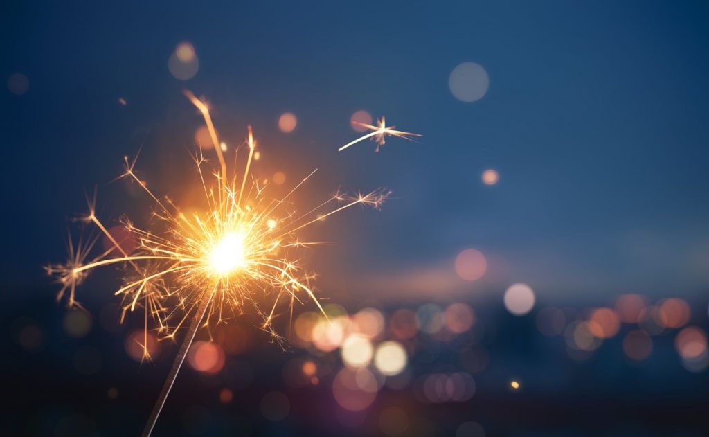 Close-up of a sparkler with out-of-focus city lights in the background