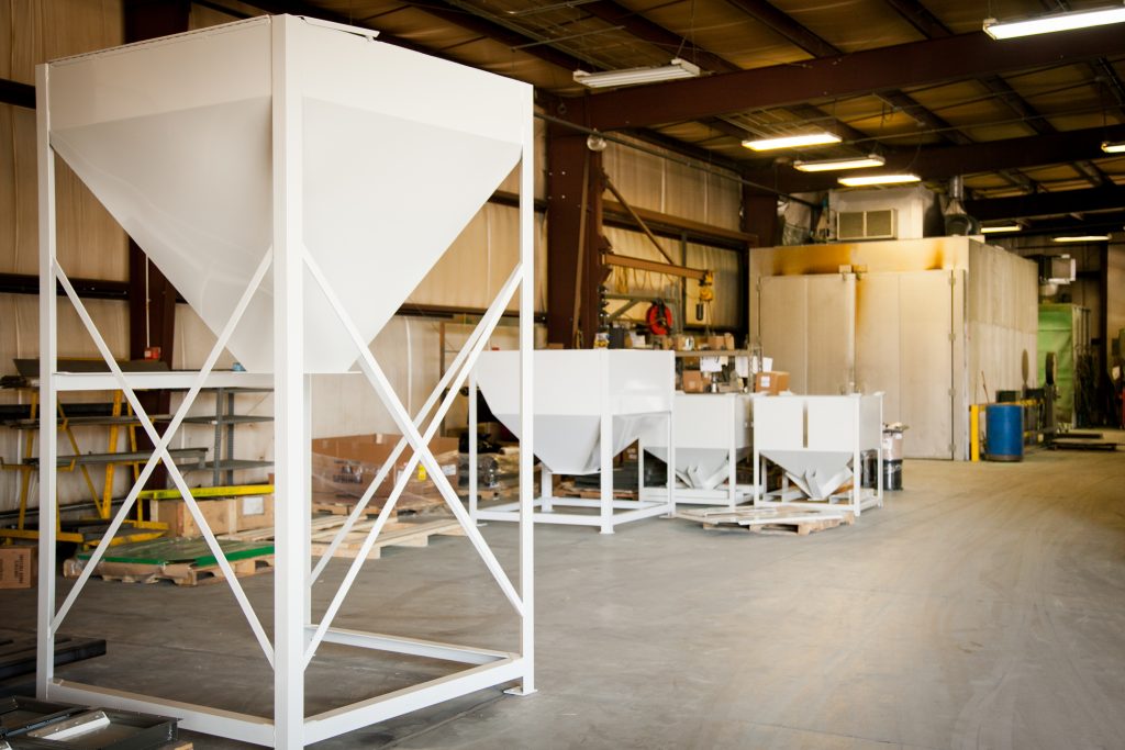 A fabrication workshop with four white industrial funnels