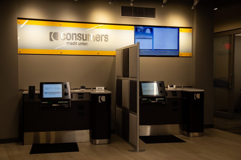 Two personal banking kiosks under a yellow Consumers Credit Union signs
