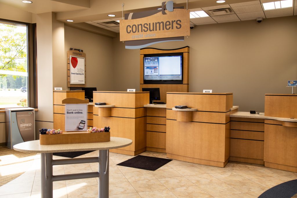 A well-lit Consumers Credit Union office with three bank teller windows