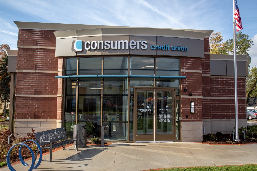 The outside of a Consumers Credit Union with a bench, trashcan, and bike rack