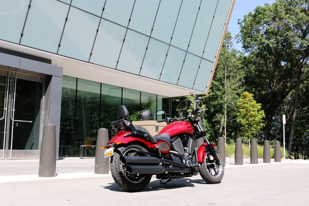 A red motorcycle parked outside of glass office doors