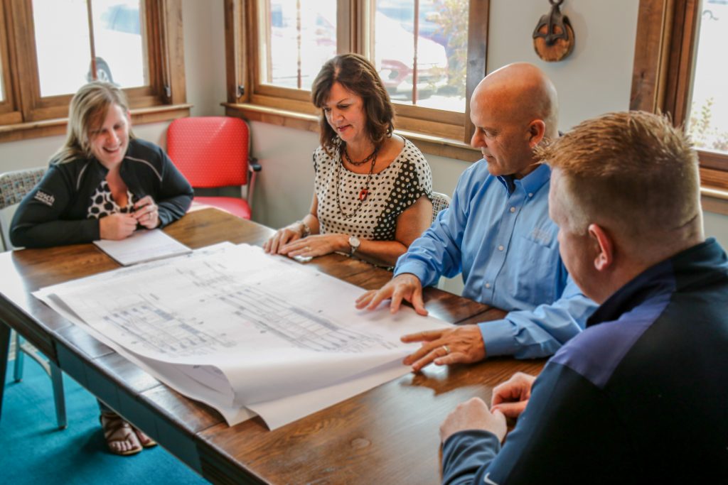 Four people looking at blueprints at a table
