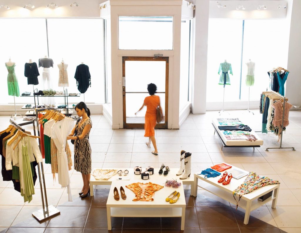 A spacious fashion boutique with two women perusing the garment racks and other displays