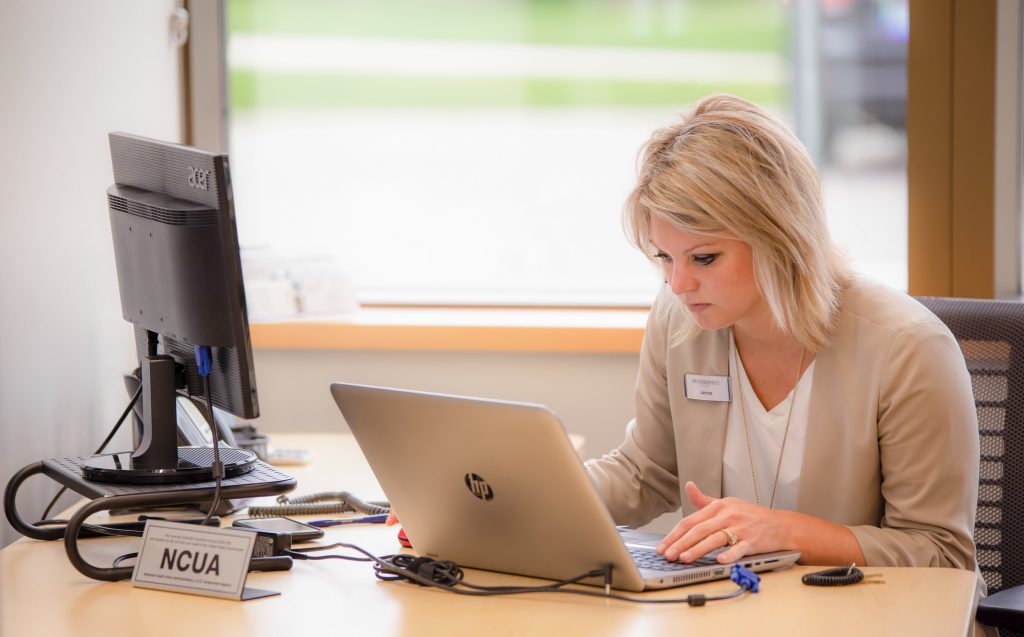 Blonde woman typing on a laptop in an office