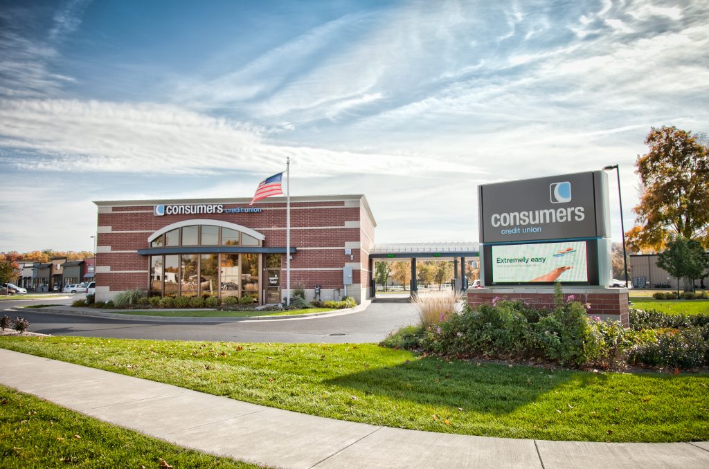 A Consumers Credit Union location on a sunny day in a large parking lot of a strip mall
