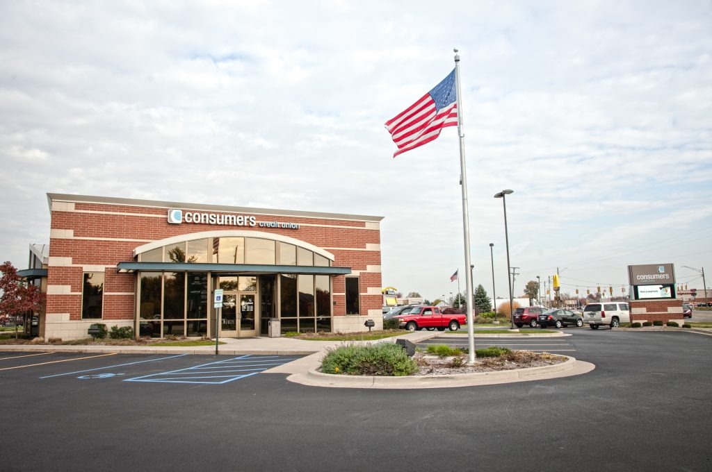 A Consumers Credit Union and a parking lot with an American Flag on a pole