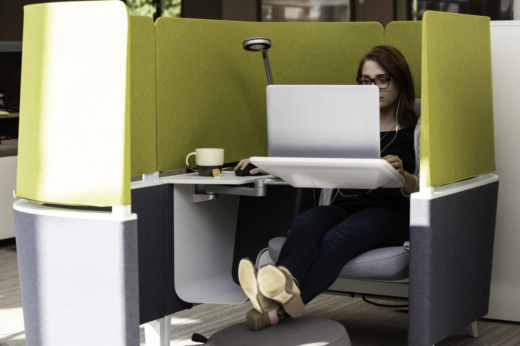 A woman working in a personal lounge cubicle on a laptop