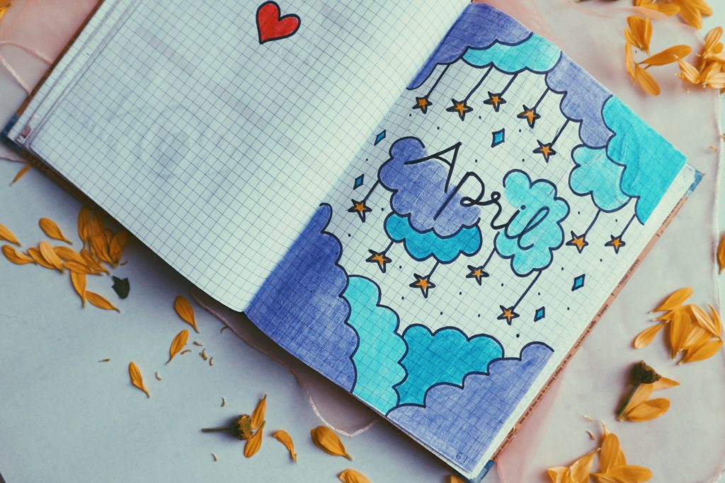 A drawing of clouds and stars with April written in the middle of the page