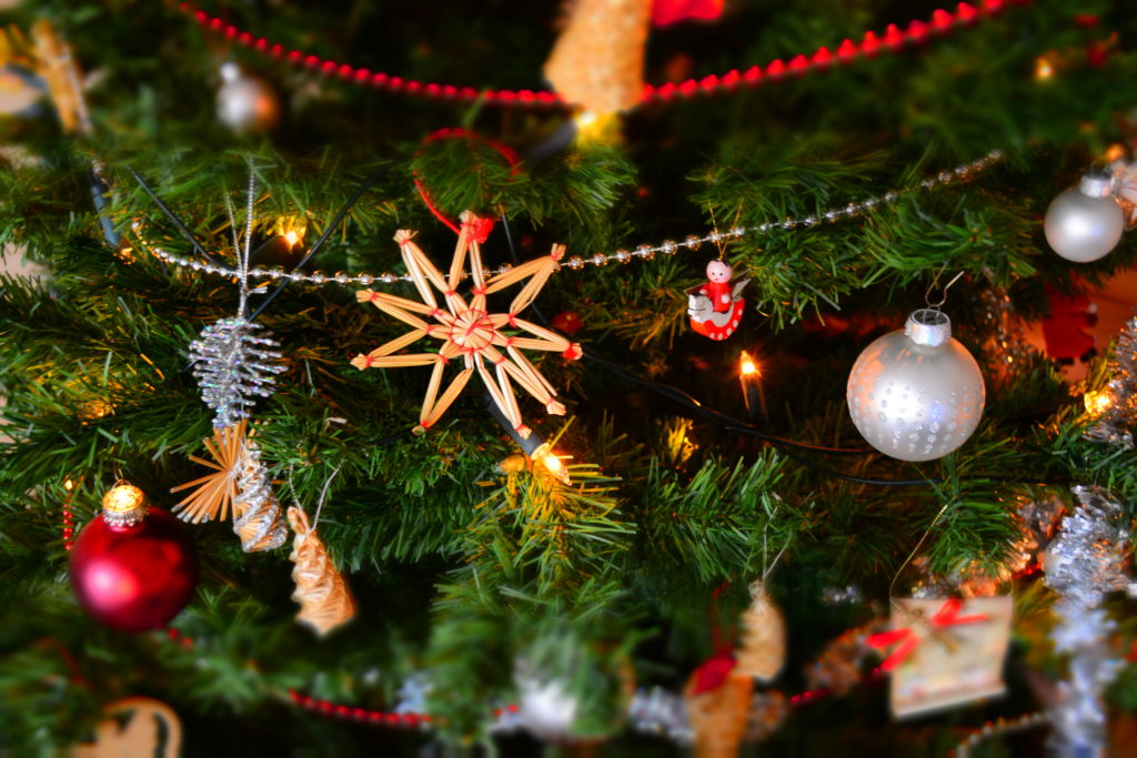 Close-up of Christmas ornaments, garlands, and string lights on a tree