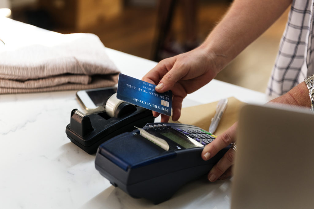 A person holding a blue credit card in the process of charging a purchase to it