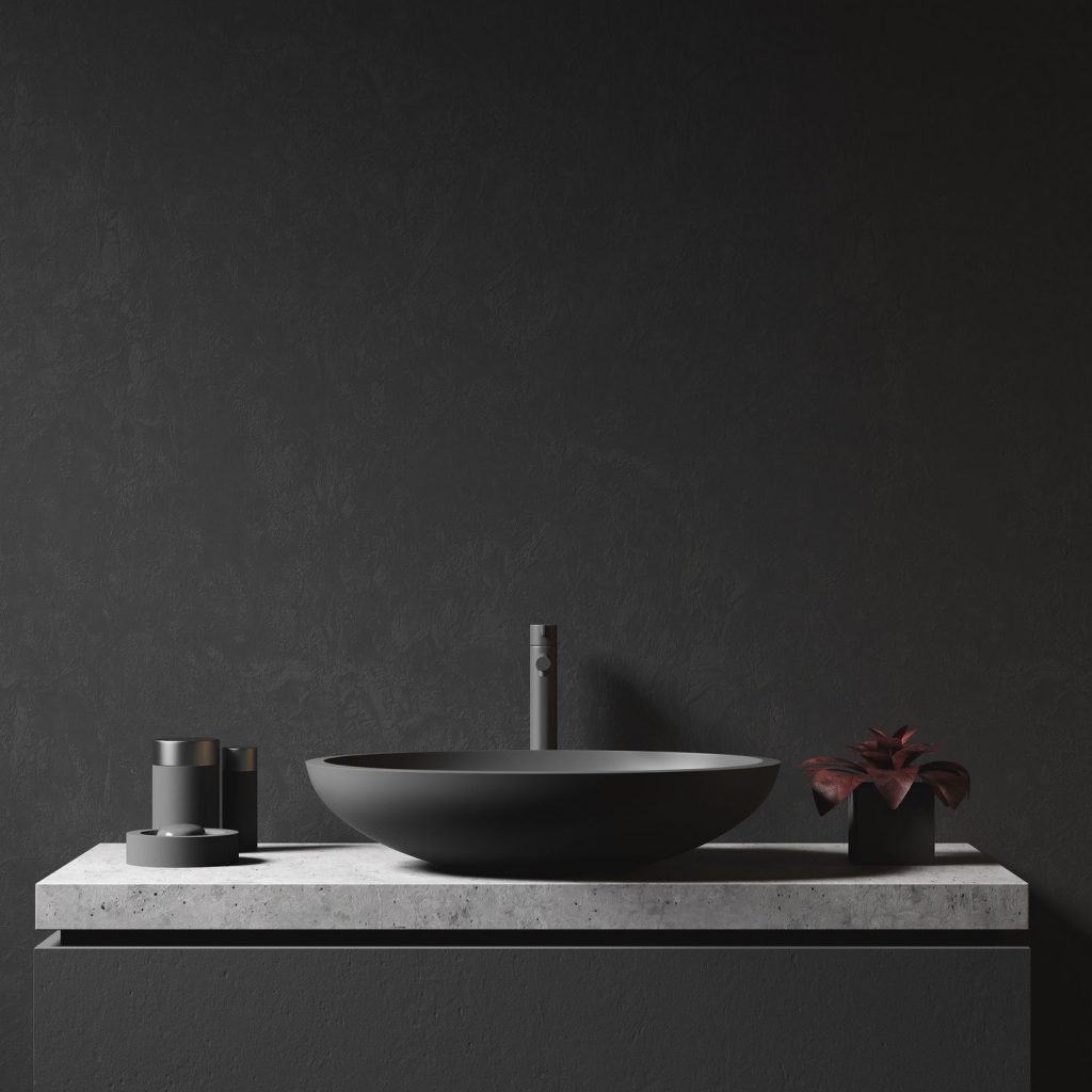 White marble vanity with a grey faucet and bowl-style sink against a dark grey wall.