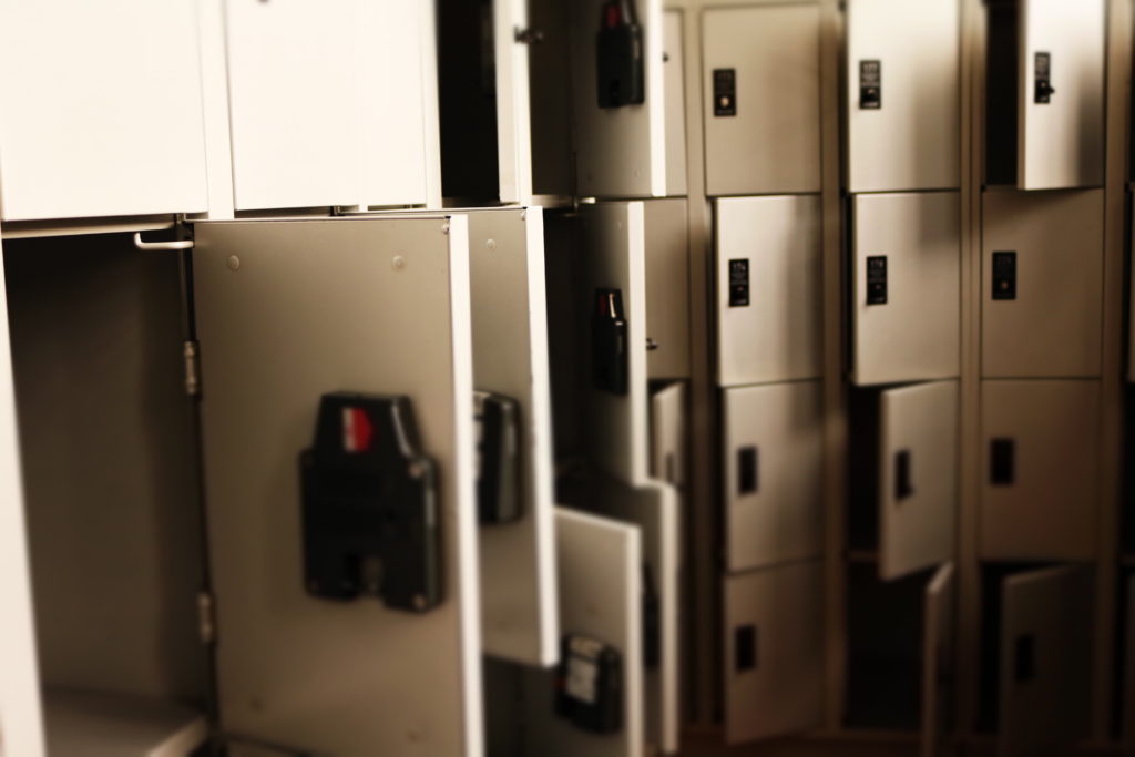 A wall of off-white lockers with some of the doors open and some closed.