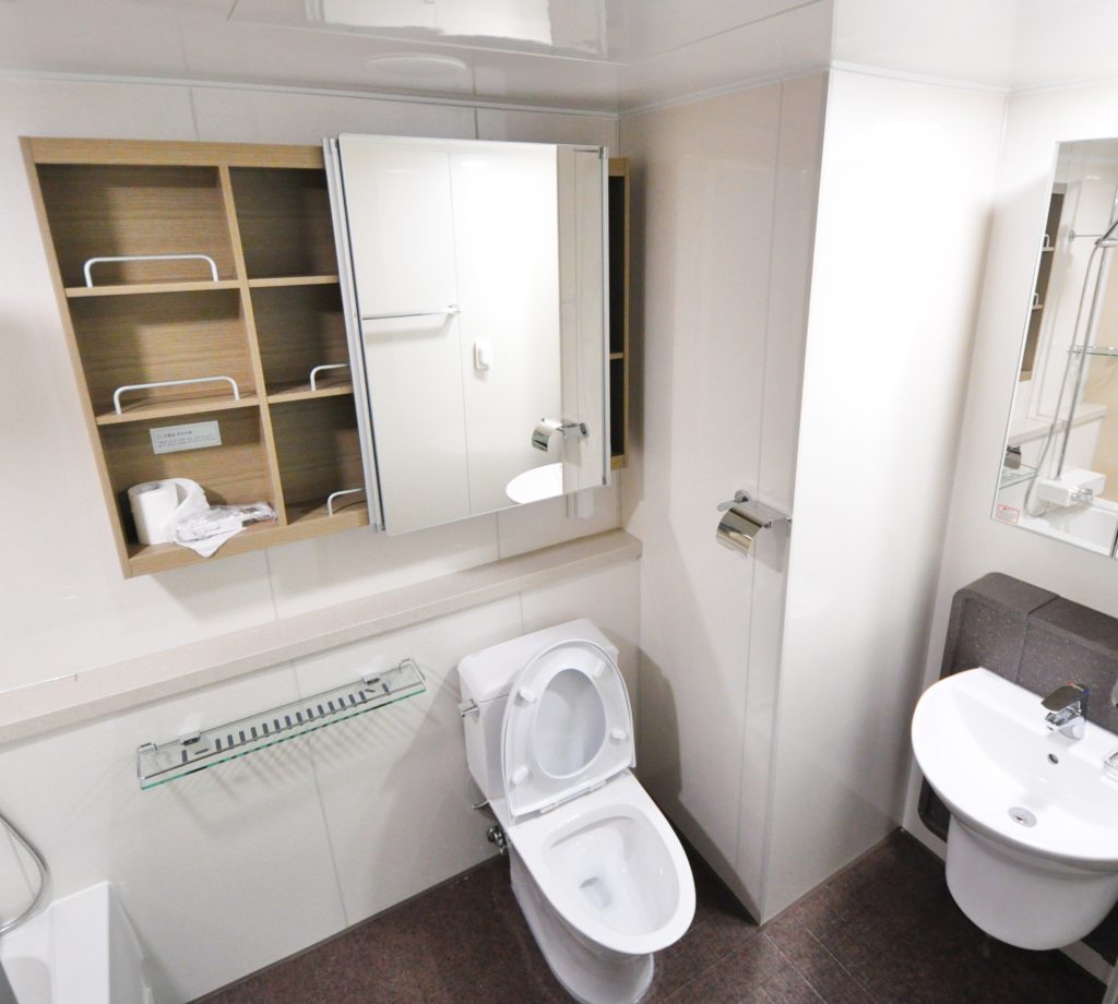 A bathroom with sliding mirror doors on a storage cabinet above a toilet.