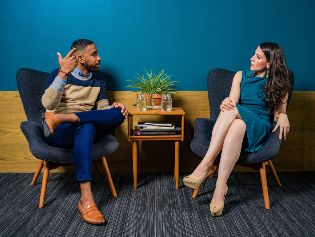 A man and a woman sitting in a lounge area in a work office talking,