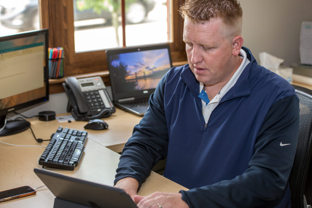 Man in personal office working on laptop.