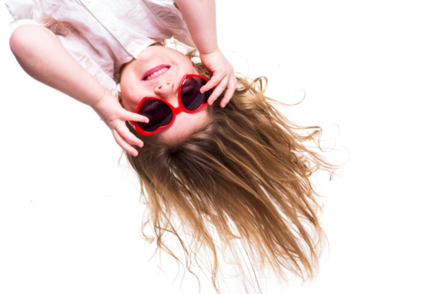 A girl with long brown hair with red heart-shaped sunglasses hanging upside down.