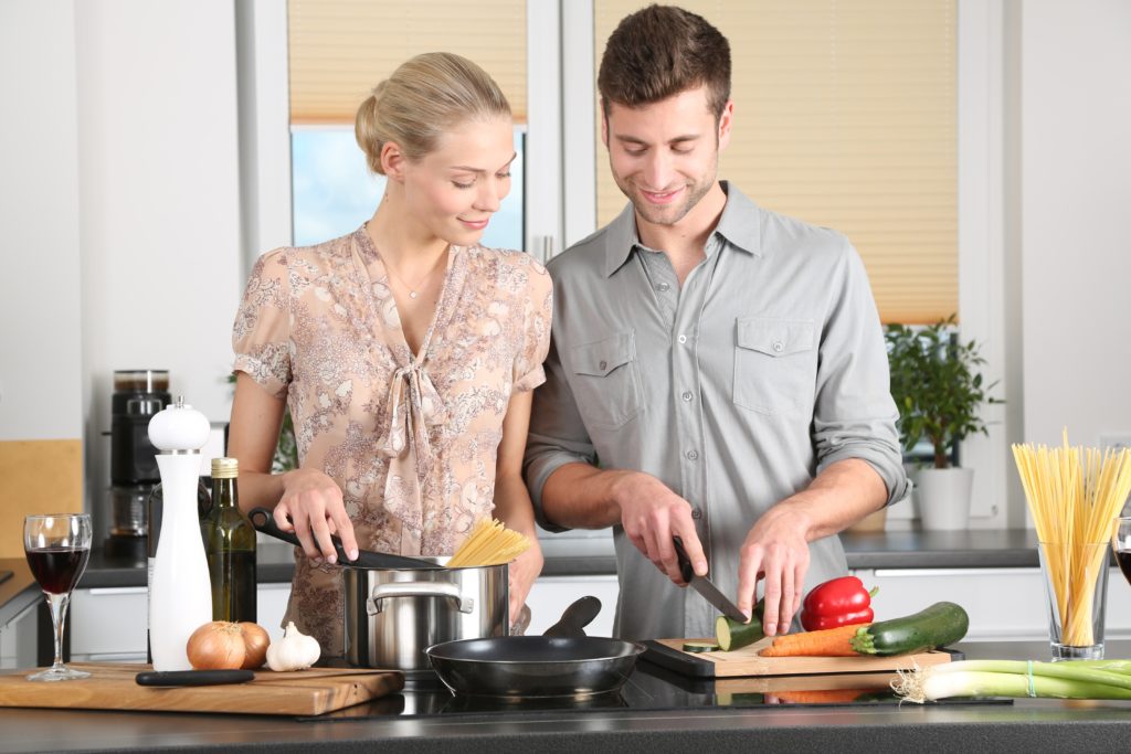 Young couple cooking together on an island with a stove.