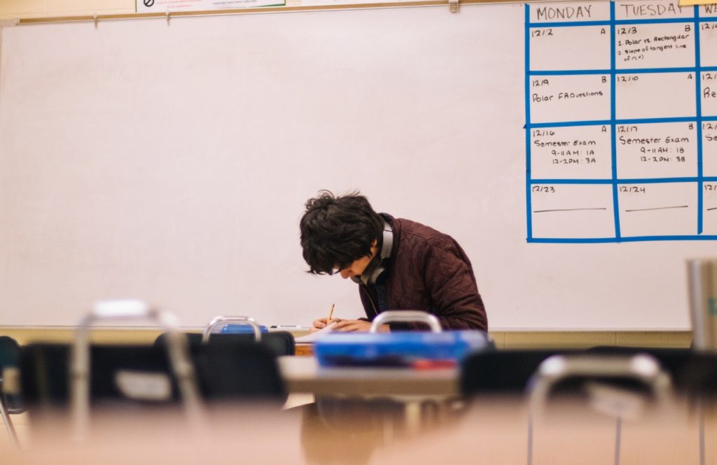 A student doing schoolwork in a lab classroom in front of a large whiteboard.