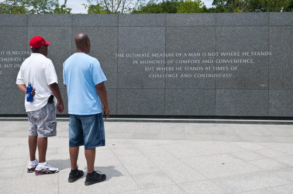 Two men observing a Martin Luther King quote on a memorial wall.
