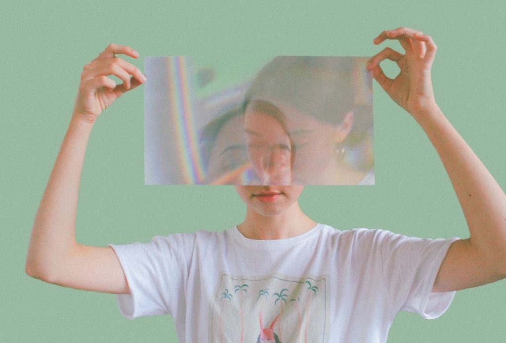 A woman holding a photo in front of her face showing a double exposure type of image.