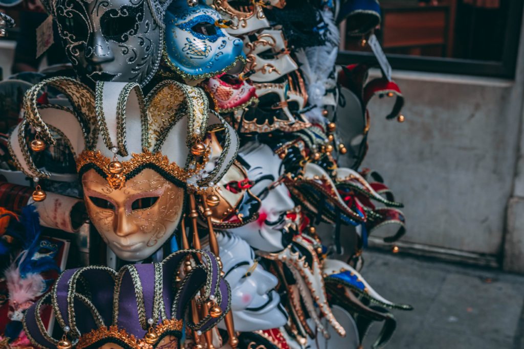 Mardi Gras masks on a rack on a sidewalk display.