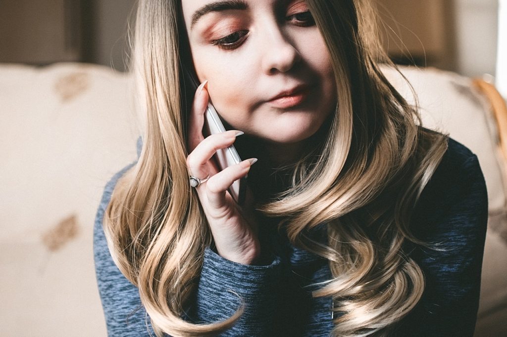 A woman speaking on a cellphone with a grey sweater.