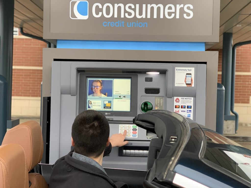 A man in a convertible banking with a TellerPlus Interactive Teller at a Consumers Credit Union.