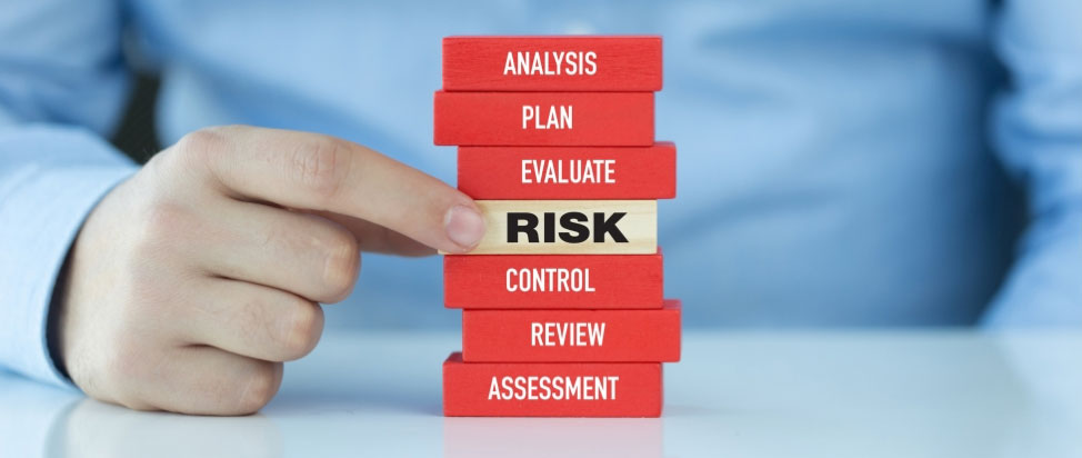Someone with a stack of red and tan rectangular blocks in front of them depicting risk assessment.