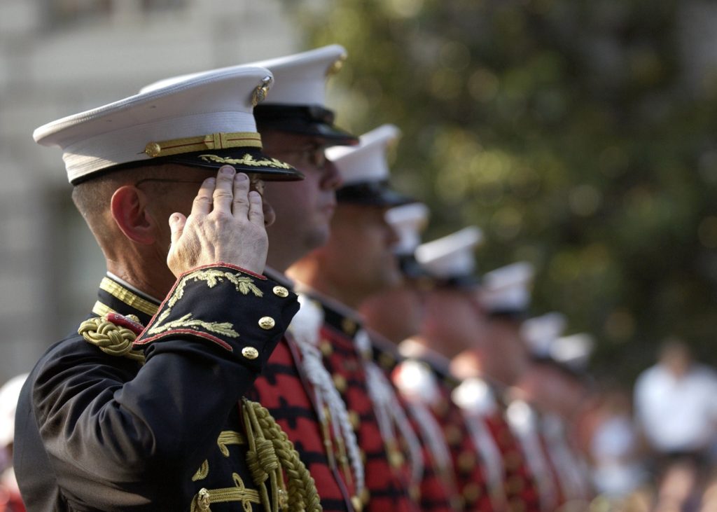 Military personnel in a line saluting.