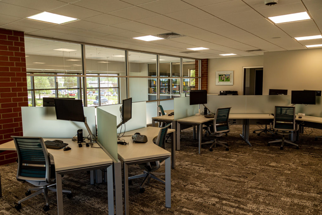 An open office setting with privacy screen dividers made of frosted glass between workstations.
