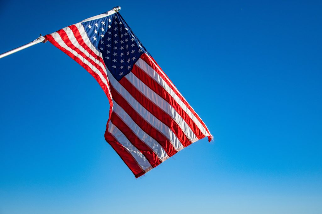 United States flag on pole against blue sky.