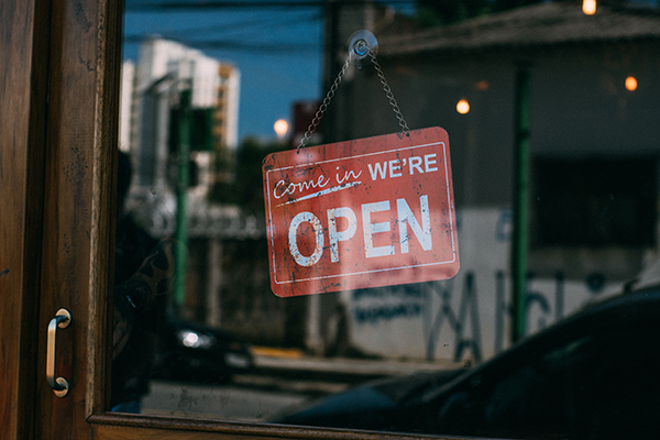 Red now open sign hanging in a business storefront.