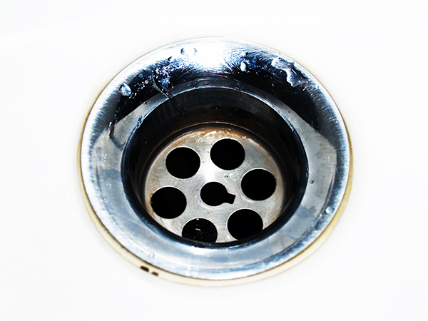 A sink drain with a touch of rust around the edges and inside of the drain.