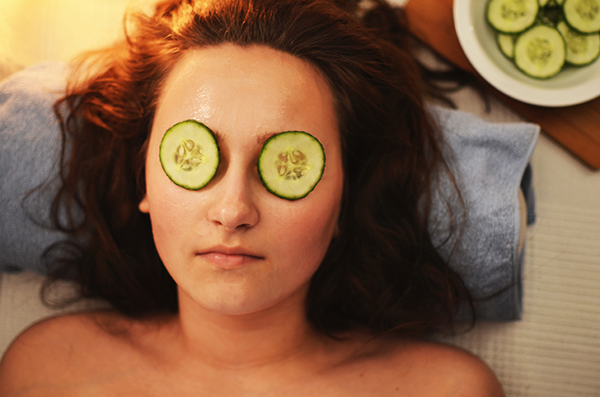 Woman at spa with cucumbers over her eyes.