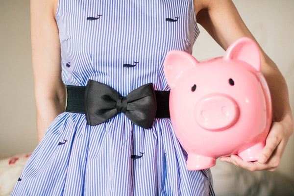Girl in blue dress holding a pink piggy bank