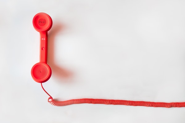 Red phone handset with red spiral cord against a white background