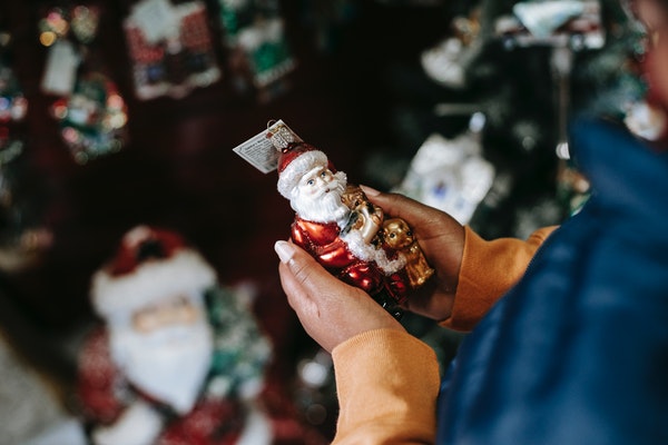 Woman holding Santa ornament in a shop.